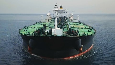 Bow and front deck of a tanker ship underway in the ocean. Aerial frontal view as crude oil tanker ploughs through waters at sea. Full loaded vessel moves at calm waters. Close up of bulbous bow break