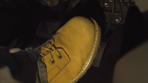 Big tan boot of male switching foot from brake to gas pedal at night in the dark 4k driving