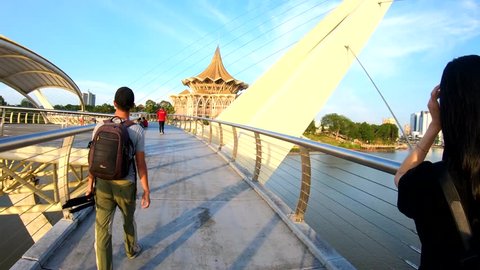 Kuching, Sarawak, Malaysia-April 11, 2019 : Hyperlapse of man walking darul hana bridge or "Jambatan Darul Hana", a landmark in Kuching waterfront, Sarawak, Malaysia