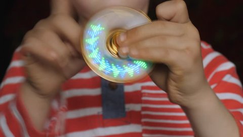 Spinning toy, spinner, in the hands of a fair-haired boy.