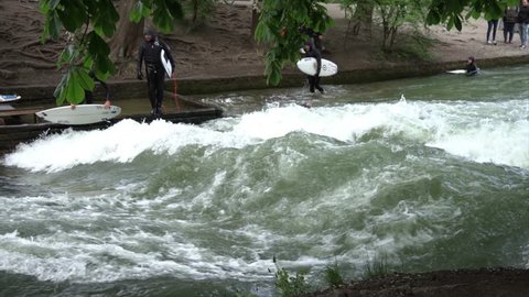 Munich/ Germany 07/05/2019: River surfing on Eisbach or Isar man made river in Munich Germany. Near the Haus der Kunst art museum, the river forms a standing wave about one meter high.