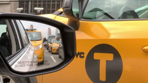 NEW YORK CITY - MAY 3, 2019: taxi cabs in rearview mirror, taxis stuck in traffic taxicab bumper-to-bumper, NYC. The yellow cabs of the city are permitted to pick up passengers in all 5 boroughs.