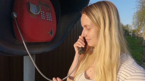 Woman having a nice conversation on the phone in call box