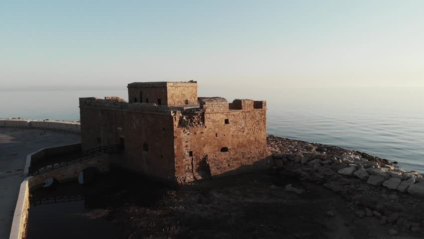 Drone aerial shot of old castle in paphos cyprus during sunset with sea in background.