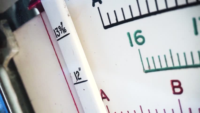 Camera slowly moves along parallel with length of face of old style scales, revealing mesaurement markings as it moves.