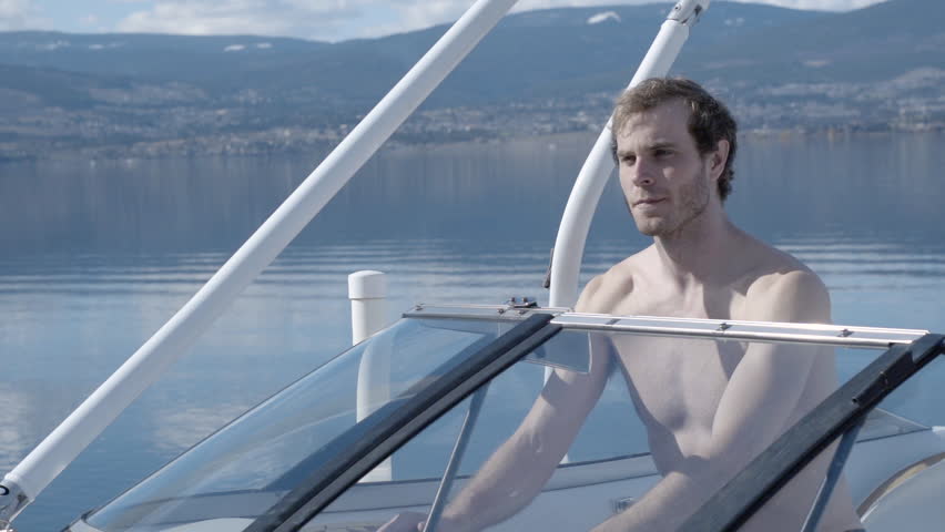 Slow Motion Close Up Attractive Shirtless Man Driving Motorboat Close To Shore In Lake In Summer