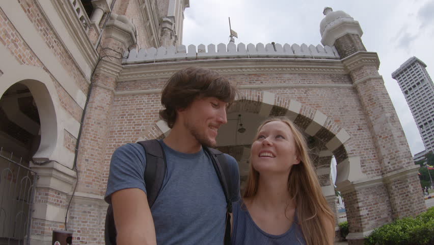 Young man and woman walking around the Sultan Abdul Samad Building in Kuala Lumpur vity, Malaysia