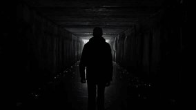 Man silhouette walking in a dark tunnel. Underground, post apocalyptic view. Exit and depression concept. People authentic video. Depression caused by coronavirus, quarantine, COVID 19. Human health 
