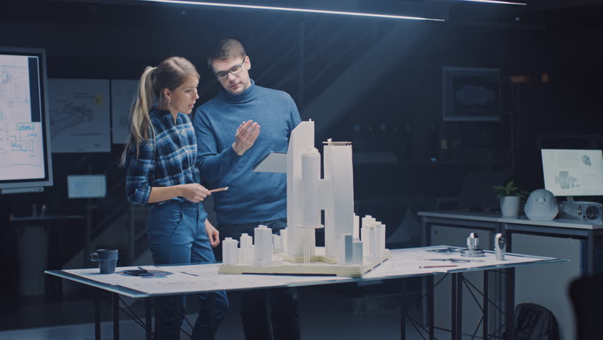 In the Creative Architectural Bureau Two Professional Engineers Work on a Model of a City District. Urban Planners Work on a Functional Building Model. They Talk and Use Digital Tablet Computer - Powered by Shutterstock - Get 15% off with code: PIKWIZARD15