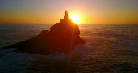 Lighthouse Silhouette on Isolated Rocky Island in Pacific Ocean During Sunset With Seagulls Flying In Background - Tillamook Rock, Oregon, USA - Left Panning Shot