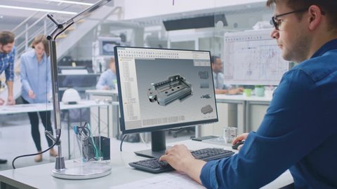 Engineer Working on Desktop Computer, Screen Showing CAD Software with 3D Component. In the Background Engineering Facility with Blueprints and Drawings with Industrial Design. Over the Shoulder