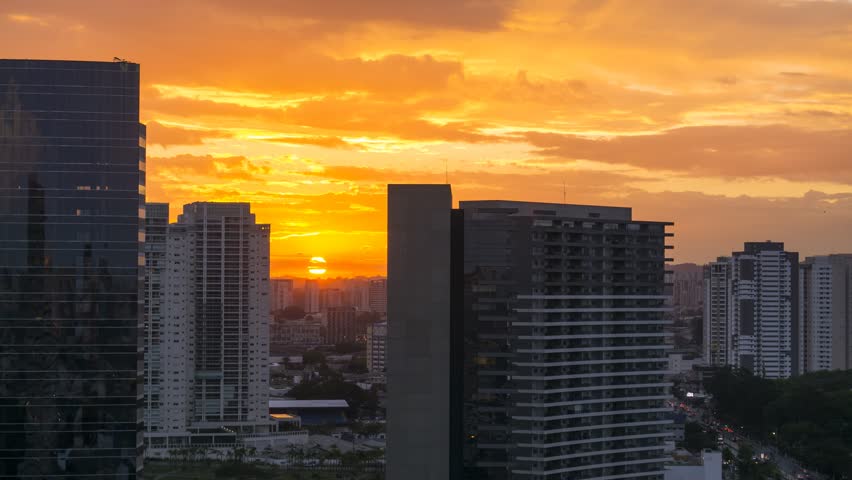 Sunset time lapse during twilight in urban landscape with cars moving on avenue and among buildings in São Paulo City Brasil