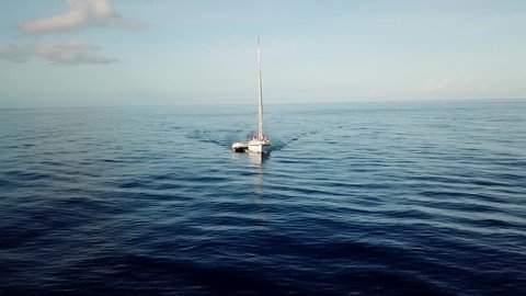 Aerial, orbit, drone shot, around a sailboat on the calm Carribbean sea, revealing green islands, rising from the sea, on a sunny, summer day, in Saint Lucia, in Lesser Antilles