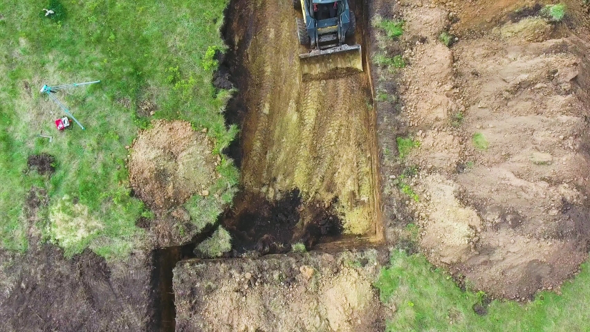 top down shot of excavator digging foundation pit for new house