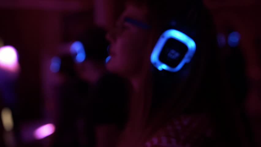 Moscow, Russia, November 2017, Happy young people are dancing and having fun at silent disco party in mansion interior. Nightlife. People listen and enjoy in music on headphones.