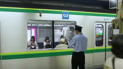 Tokyo / Japan - April 21st 2018: Platform attendant (Oshiya) making sure all passengers are aboard as train leaves at Meiji-jingumae Harajuku Station of Tokyo Metro Subway