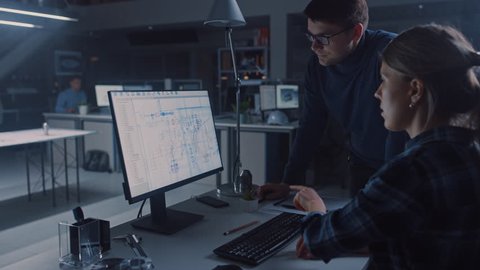 Engineer Working on Desktop Computer, Screen Showing CAD Software with Technical Blueprints, Her Male Project Manager Explains Job Specifics. Industrial Design Engineering Facility Office