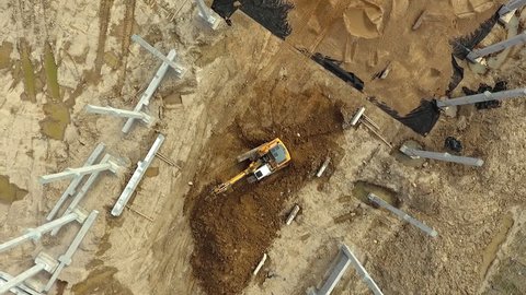 Aerial flight over new constructions site development where heavy machinery and construction workers are working with power tools in Eastern Europe, Lithuania, Alytus city outskirts. During cloudy day