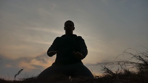 religion concept. silhouette of a male monk engaged in meditation at sunset sunlight. Buddhist lifestyle prayer at sunset healthy way of life nature