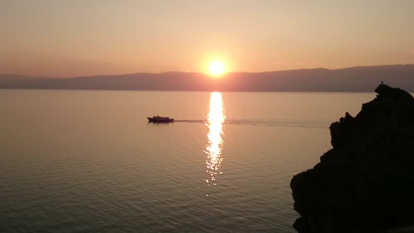 Panorama of Lake Baikal. Over the water, the ship is sailing in the sunset. Evening. Sunset. Horizon. Summer. Russia.