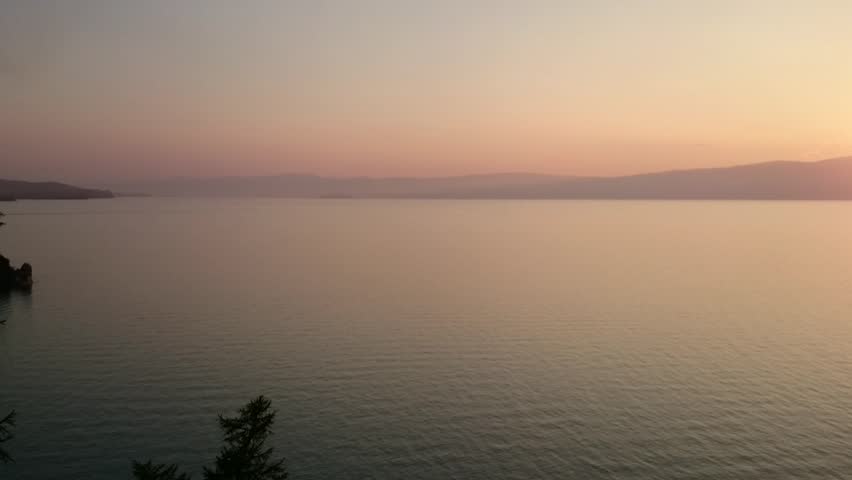 Panorama of Lake Baikal. Over the water, the ship is sailing in the sunset. Evening. Sunset. Horizon. Summer. Russia.