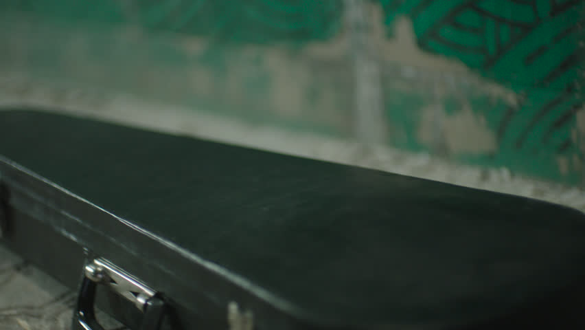  Men's hands folding violin into case.