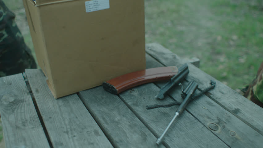 The hands of the militaries collect weapons on the table.