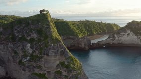 Aerial view of the green tropical coast of the island of Nusa Penida, Atuh beach, Bali, Indonesia.Clear blue ocean waves rolling to the beach. 4K