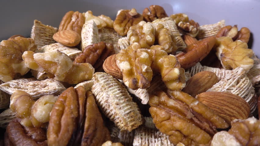 Slow motion close POV reverse dolly shot of a bowl of bite size wheat cereal and assorted nuts.