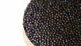 Black Caviar rotated background. High quality real natural sturgeon black caviar close-up, rotation. Delicatessen. Texture of expensive luxury caviar in tin can on white. Seafood. 4K UHD video Slowmo