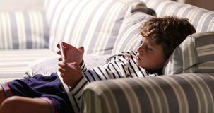 Young boy in sofa holding tech cellphone device playing video game