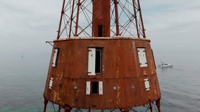Aerial drone video of Carysfort Reef light house in Key Largo Florida. Historic lighthouse standing over shallow reef in the ocean.
