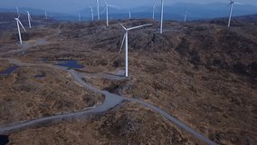 Windmills in Norwegian mountains. Tilted and panning drone video. Small ponds in background.