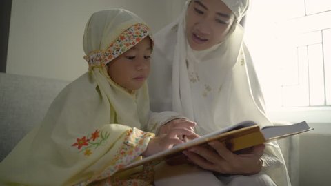 muslim parent and daughter reading quran after praying together