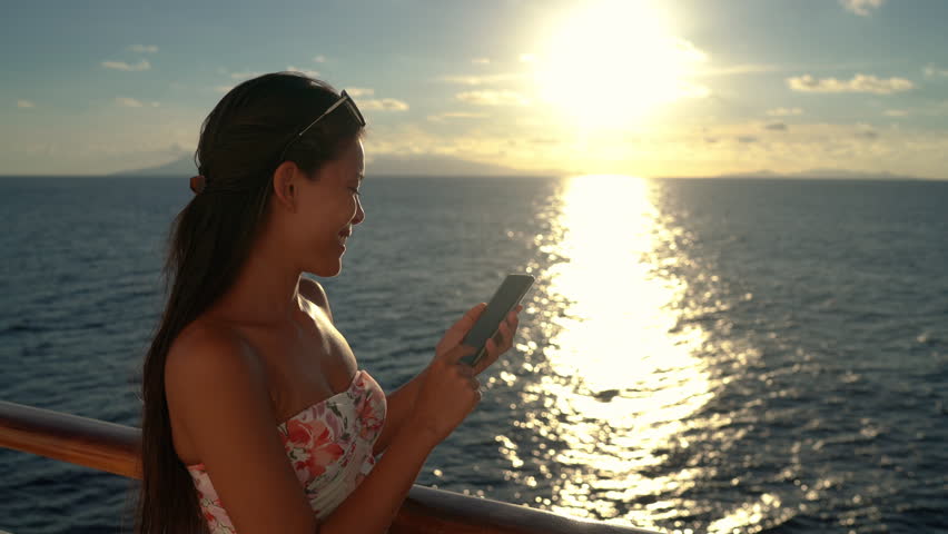 People using phones - Woman using mobile smart phone on Cruise ship vacation travel woman enjoying sunset at sea on boat with beautiful sunset on travel at sea.