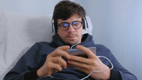 Man in glasses and earphones online browsing on smartphone. Face close-up