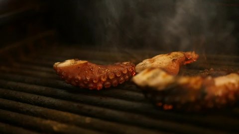 Delicious octopus being cooked on the blazing grill.