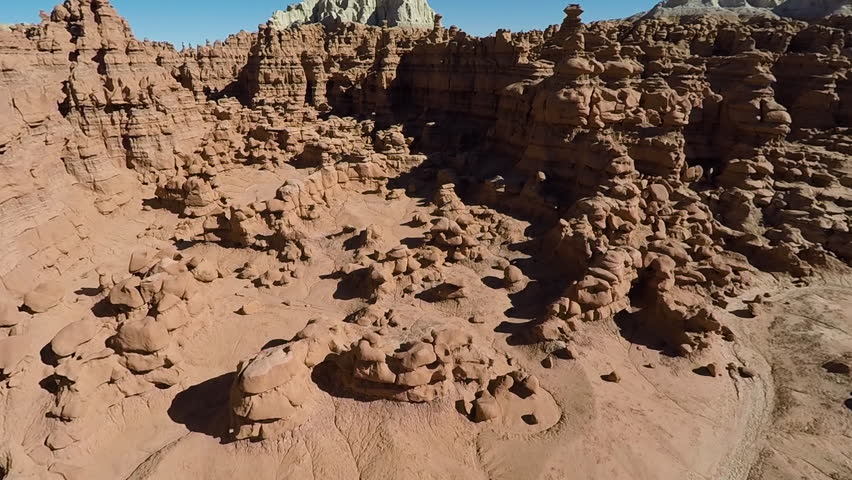 Aerial shot flying over unique rock formations in the Goblin Valley, Utah, on a clear sunny day