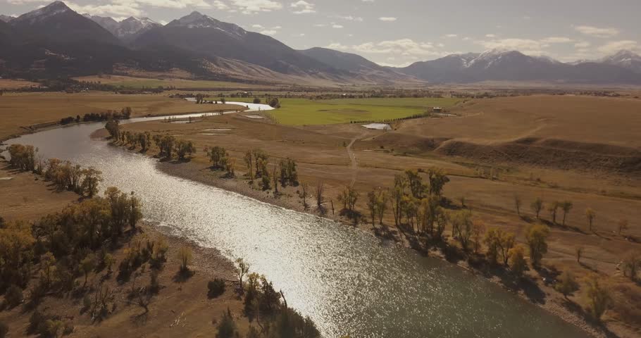 Beautiful narrow yellowstone river stream in high plains of southern Montana on a bright day (drone shot)