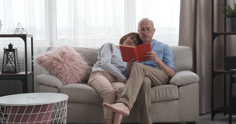 Senior man reading a book to his wife at home