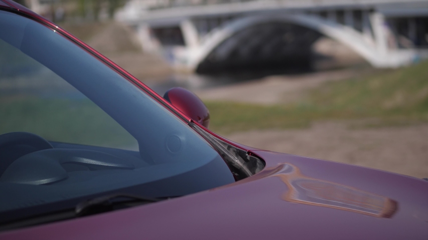 The girl lies on the windshield, gently smiles and strokes the car.