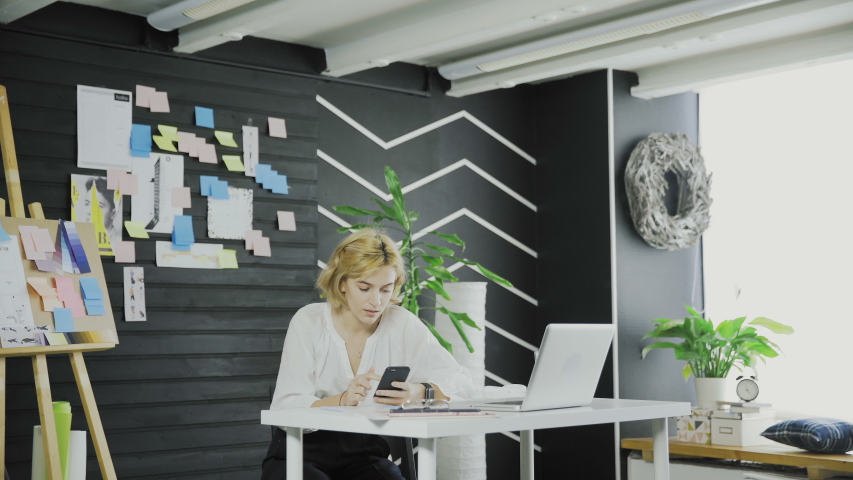Attractive business woman lookinh at the cell phone and then writing something on the board