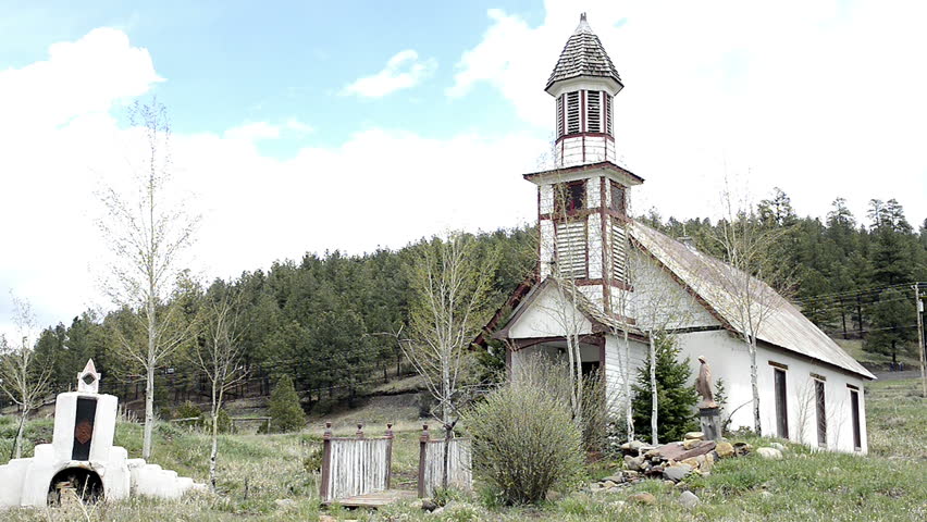 PAGOSA SPRINGS. COLORADO - May 2014: An old church sits abandoned and for sale in the outskirts of Pagosa Springs, Colorado as a light breeze stirs tree branches just starting to bud out into leaf.