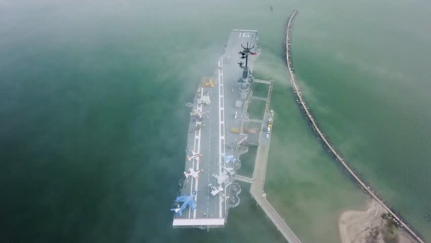 Drone flying over aircraft carrier in Corpus Christi looking down on the flight deck in the fog that passes over the navy ship stuck on a sandbar in the gulf.