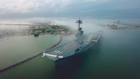 Drone flying around aircraft carrier in Corpus Christi looking at the front of the flight deck in the fog that passes over the navy ship stuck on a sandbar in the gulf.
