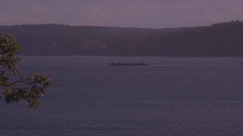Puget Sound, Washington State. Viewing non-descript container ship, while overlooking Saratoga Passage, between Camano and Whidbey Island during late afternoon, Spring season.