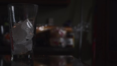 Soda being poured into a glass with ice inside of it on a countertop