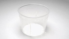 Pink syrup medicine being poured into a clear plastic measuring cup. LOCKED DOWN SHOT. - Powered by Shutterstock - Get 15% off with code: PIKWIZARD15