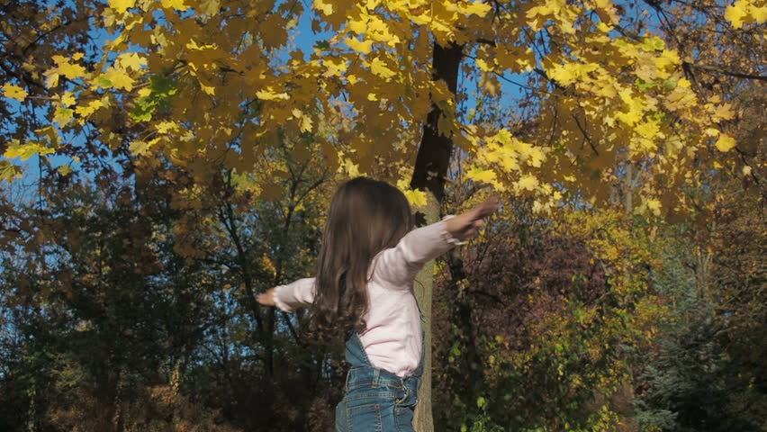 A happy child is spinning in nature. Little girl whirls in the autumn park.