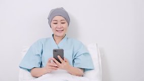 Senior asian woman patient talking to her grand children on mobile phone on hospital bed. Senior technology life style concept.